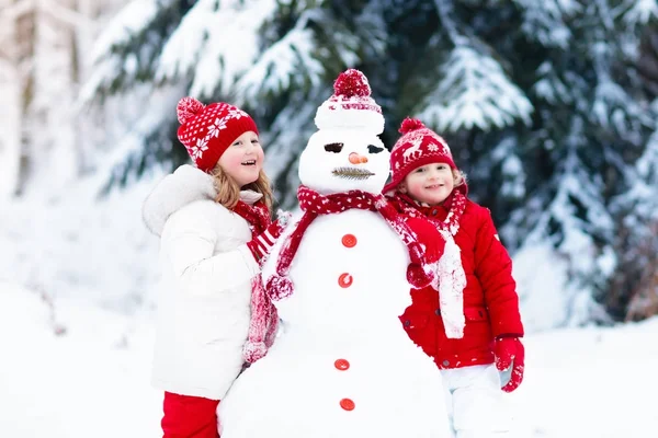 Des enfants construisant un bonhomme de neige. Des enfants dans la neige. Amusement d'hiver . — Photo