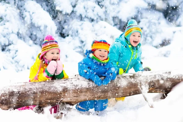 Niños jugando en la nieve. Los niños juegan al aire libre en invierno nevadas . — Foto de Stock