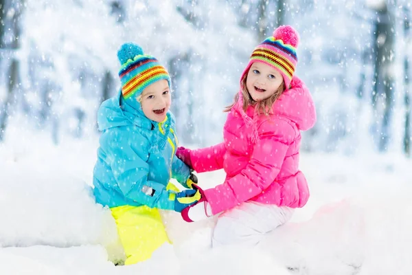 Kinderen spelen in de sneeuw. Kinderen spelen buiten in de winter sneeuwval. — Stockfoto