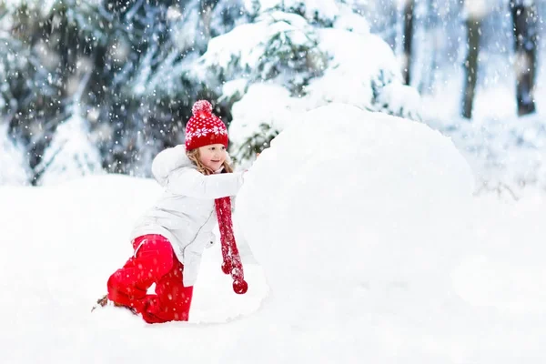 Des enfants construisant un bonhomme de neige. Des enfants dans la neige. Amusement d'hiver . — Photo