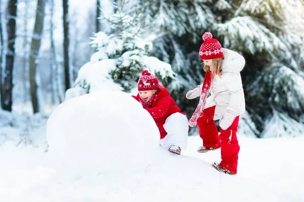 Des enfants construisant un bonhomme de neige. Des enfants dans la neige. Amusement d'hiver . — Photo