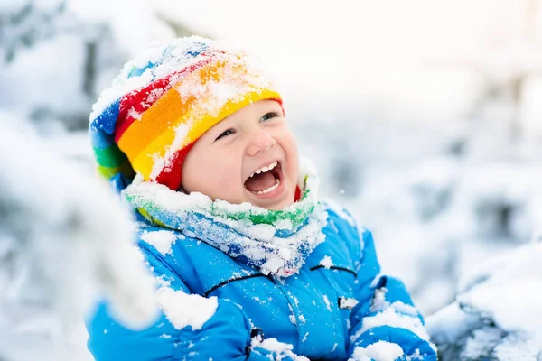 Μωρό παίζει με το χιόνι το χειμώνα. Παιδί στη χιονισμένη πάρκο. — Φωτογραφία Αρχείου