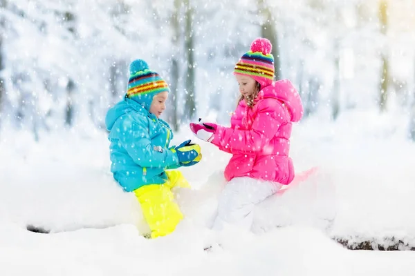 Kids playing in snow. Children play outdoors in winter snowfall. — Stock Photo, Image