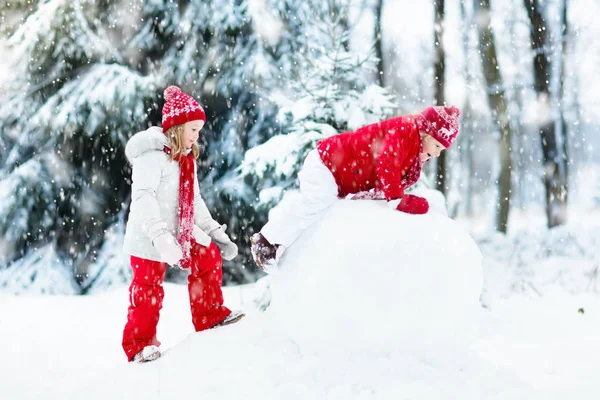 Des enfants construisant un bonhomme de neige. Des enfants dans la neige. Amusement d'hiver . — Photo