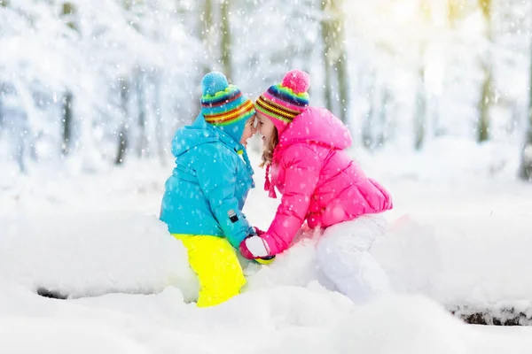 Kinderen spelen in de sneeuw. Kinderen spelen buiten in de winter sneeuwval. — Stockfoto
