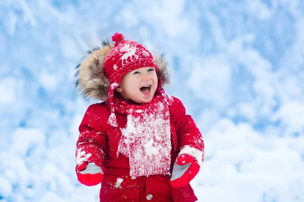 Barnet leker med snö på vintern. — Stockfoto