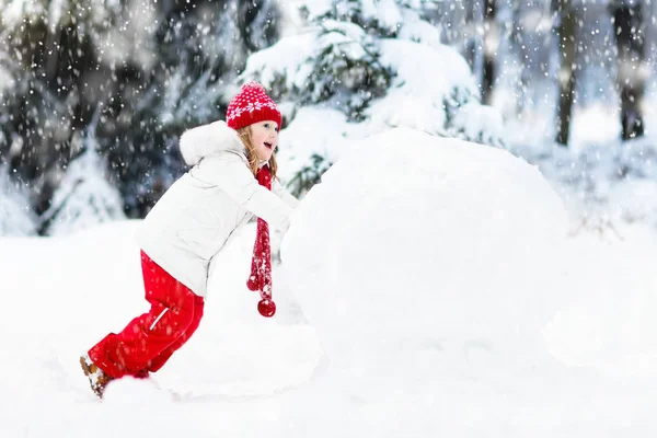 Des enfants construisant un bonhomme de neige. Des enfants dans la neige. Amusement d'hiver . — Photo
