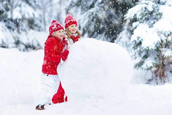 Des enfants construisant un bonhomme de neige. Des enfants dans la neige. Amusement d'hiver . — Photo