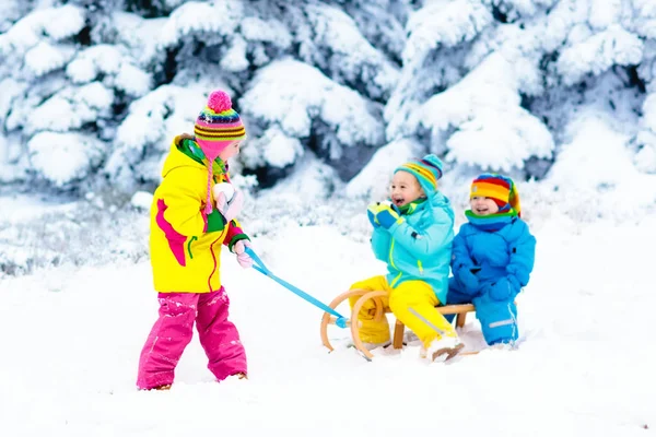 Miúdos em viagem de trenó. Crianças a patinar. Inverno neve diversão . — Fotografia de Stock