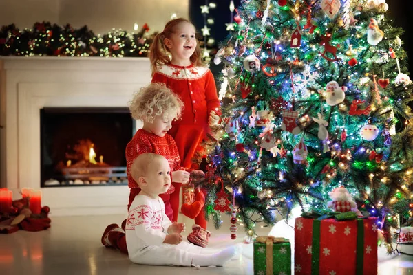 Niños en el árbol de Navidad. Niños en la chimenea en Nochebuena —  Fotos de Stock