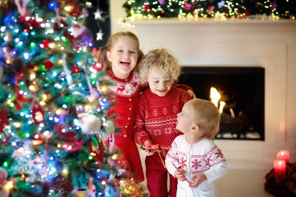 Children at Christmas tree. Kids at fireplace on Xmas eve — Stock Photo, Image