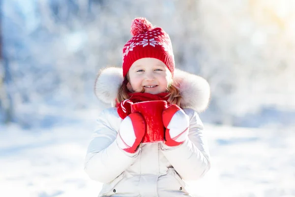 Kind drinken warme chocolademelk in winter park. Kinderen in de sneeuw op Chr — Stockfoto