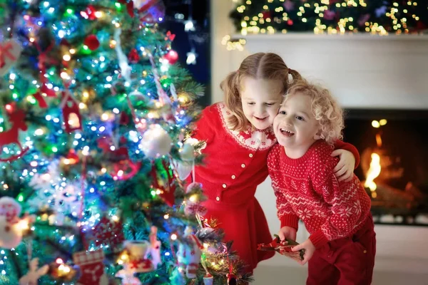 Niños en el árbol de Navidad. Niños en la chimenea en Nochebuena — Foto de Stock