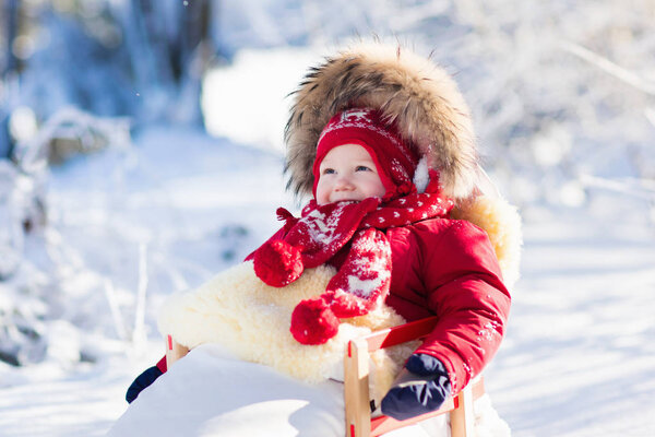 Sled and snow fun for kids. Baby sledding in winter park.