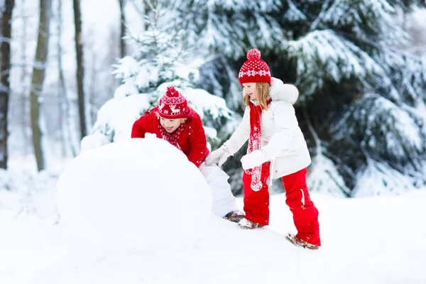 Des enfants construisant un bonhomme de neige. Des enfants dans la neige. Amusement d'hiver . — Photo