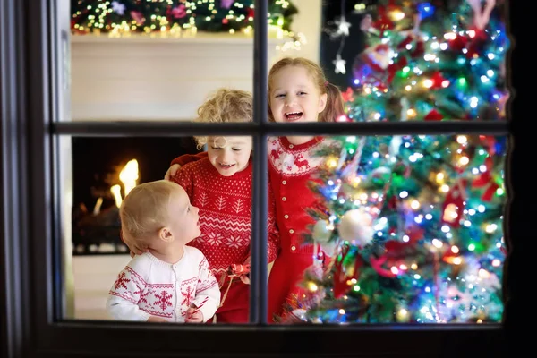 Niños en el árbol de Navidad. Niños en la chimenea en Nochebuena — Foto de Stock