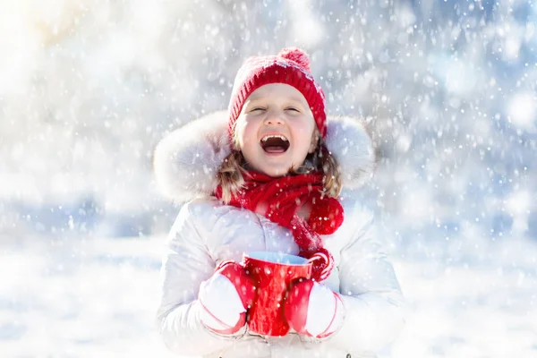 Niño bebiendo chocolate caliente en el parque de invierno. Niños en la nieve en Chr —  Fotos de Stock