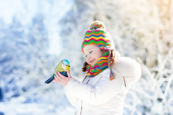 Dítě krmení ptáků v zimě parku. Děti hrají ve sněhu. Příroda a — Stock fotografie