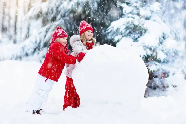 Des enfants construisant un bonhomme de neige. Des enfants dans la neige. Amusement d'hiver . — Photo