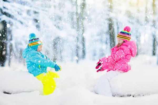 Crianças brincando na neve. Crianças brincam ao ar livre no inverno snowfall . — Fotografia de Stock