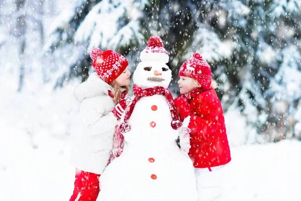 子供たちは雪だるまを構築します。雪の子どもたち。冬の楽しみ. — ストック写真