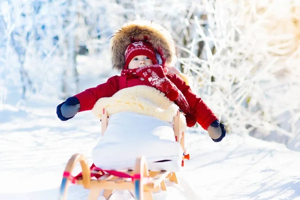 Slee en de sneeuw pret voor kinderen. Baby rodelen in winter park. — Stockfoto