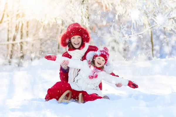 Luge mère et enfant. Amusement hivernal de neige. Famille en traîneau . — Photo