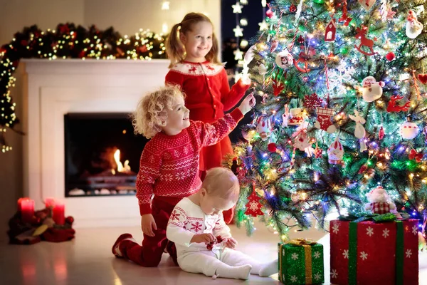 Kinder am Weihnachtsbaum. Kinder am Kamin an Heiligabend — Stockfoto