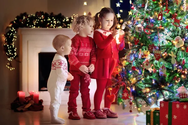 Niños en el árbol de Navidad. Niños en la chimenea en Nochebuena —  Fotos de Stock