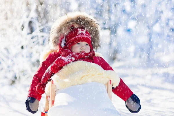 Sanki i śnieżne zabawy dla dzieci. Dziecko na sankach w winter park. — Zdjęcie stockowe