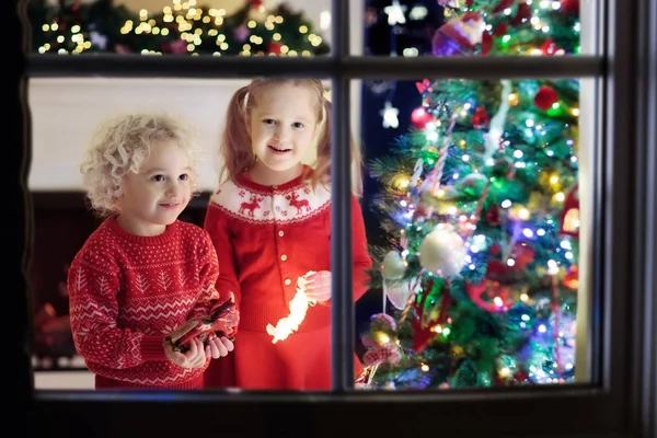 Niños en el árbol de Navidad. Niños en la chimenea en Nochebuena —  Fotos de Stock