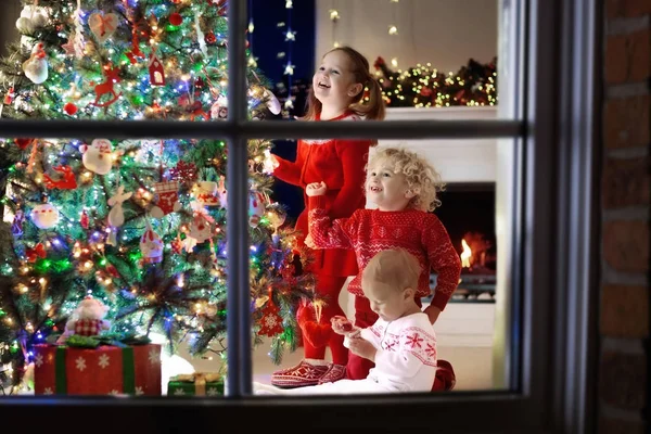 Children at Christmas tree. Kids at fireplace on Xmas eve — Stock Photo, Image