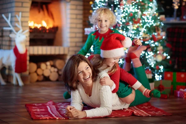 Familie mit Kindern am Weihnachtsbaum und Kamin. — Stockfoto