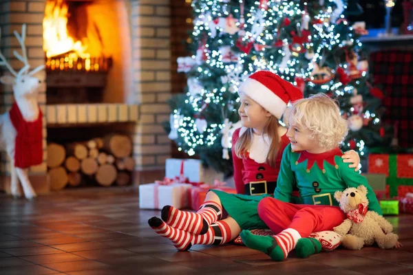 Kind am Weihnachtsbaum. Kinder am Kamin an Weihnachten — Stockfoto