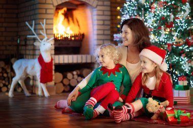Noel ağacı ve şömine çocuklu aile. 