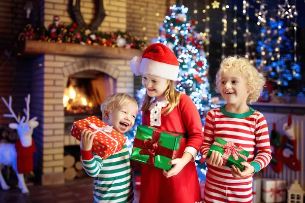 Kind am Weihnachtsbaum. Kinder am Kamin an Weihnachten — Stockfoto