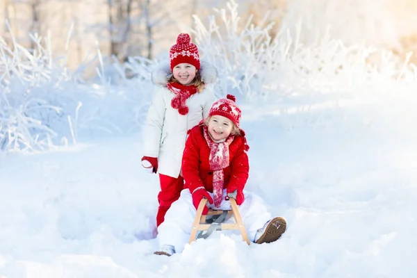 Τα παιδιά παίζουν στο χιόνι. Χειμώνας έλκηθρο βόλτα για παιδιά — Φωτογραφία Αρχείου