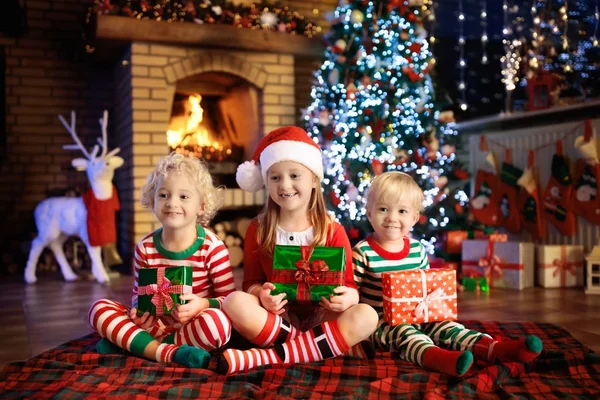 Kind in de kerstboom. Kinderen bij de open haard op Xmas — Stockfoto