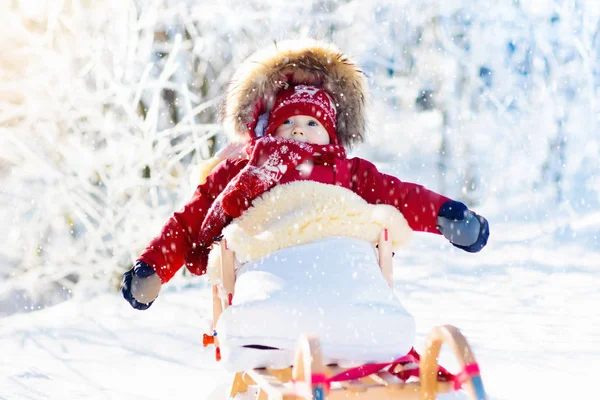 Trineo y diversión de nieve para los niños. Bebé trineo en el parque de invierno . —  Fotos de Stock