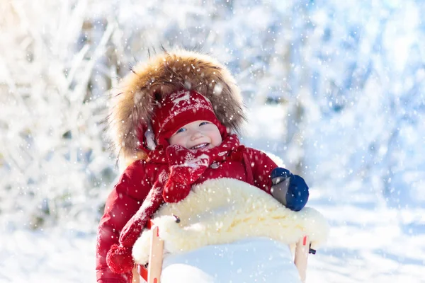 Trineo y diversión de nieve para los niños. Bebé trineo en el parque de invierno . —  Fotos de Stock