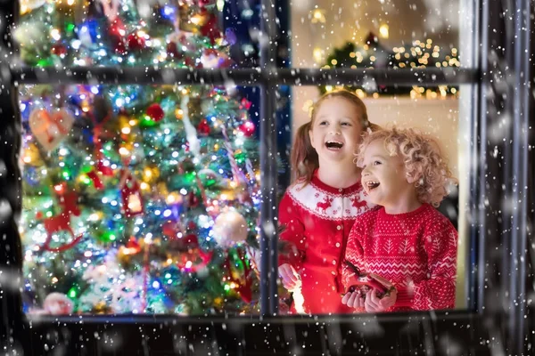 Niños en el árbol de Navidad. Niños en la chimenea en Nochebuena — Foto de Stock