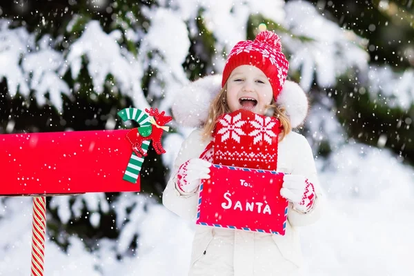 Dítě s dopis do Santa na Vánoce mail box ve sněhu — Stock fotografie