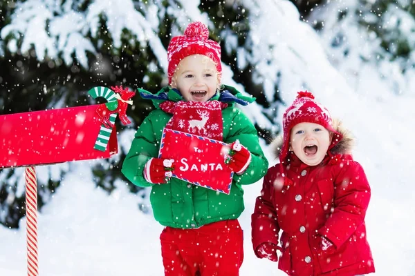 Dítě s dopis do Santa na Vánoce mail box ve sněhu — Stock fotografie