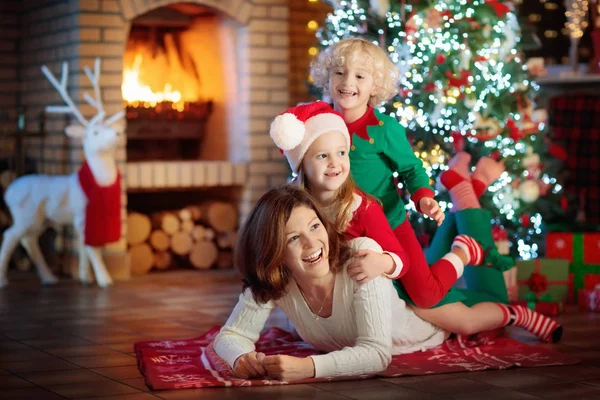 Familie mit Kindern am Weihnachtsbaum und Kamin. — Stockfoto