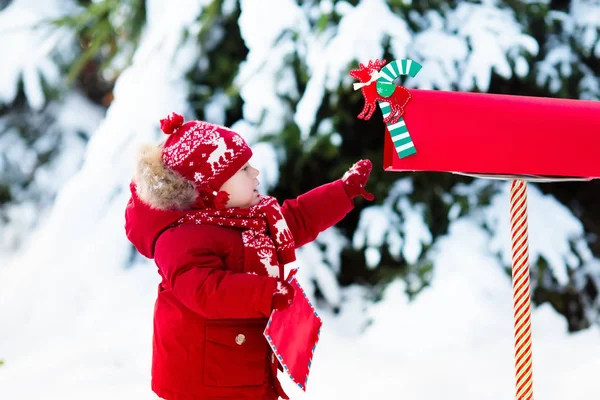 Niño con carta a Santa en el buzón de Navidad en nieve —  Fotos de Stock