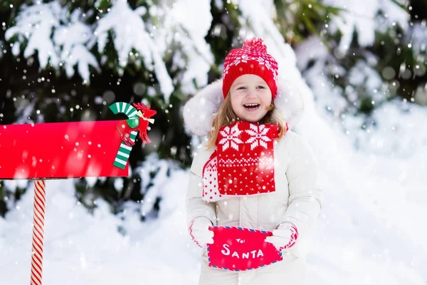 Niño con carta a Santa en el buzón de Navidad en nieve — Foto de Stock