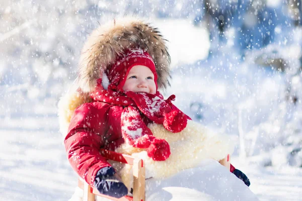 Slee en de sneeuw pret voor kinderen. Baby rodelen in winter park. — Stockfoto