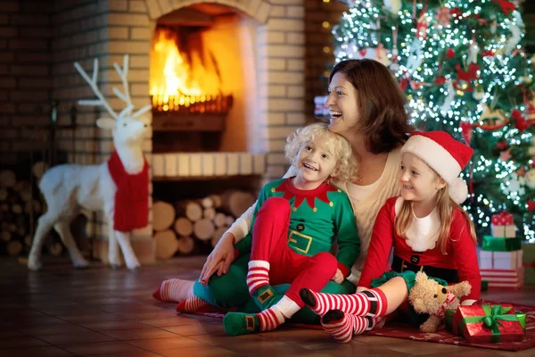 Keluarga dengan anak-anak di pohon Natal dan perapian . — Stok Foto
