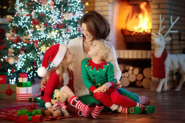Familie mit Kindern am Weihnachtsbaum und Kamin. — Stockfoto
