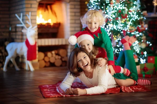 Famiglia con bambini all'albero di Natale e camino . — Foto Stock
